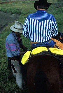 Alex adjusts a rider's saddle.